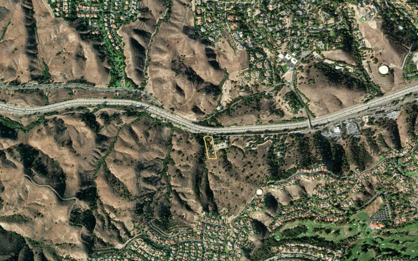 Wider aerial showing the parcel between the 101 Freeway and the hillside neighborhoods of Calabasas